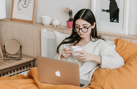 Woman sitting in bed and looking at her laptop