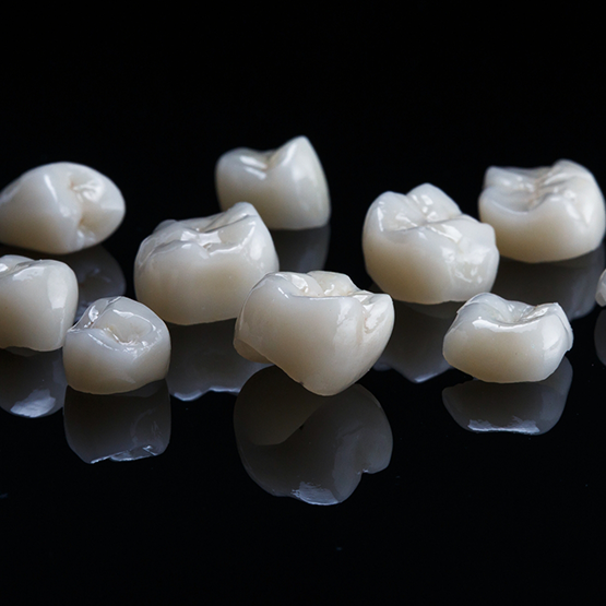 Several tooth colored dental crowns against a black background