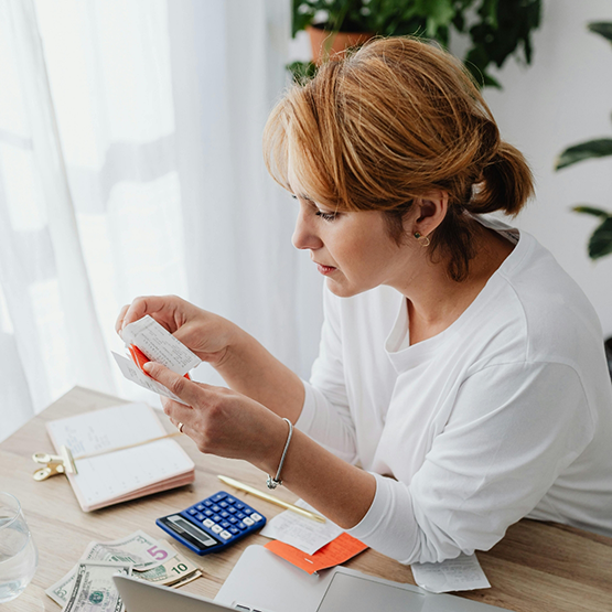 Woman at a desk looking through receipts while typing on a calculator