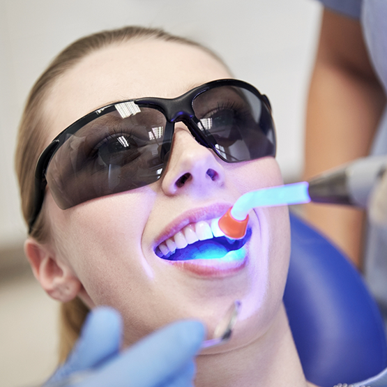 Dental patient having an ultraviolet light shone onto her tooth