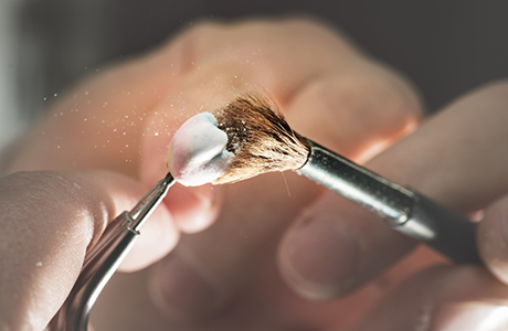 Close up of a dental crown being brushed with a tiny brush
