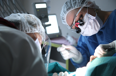 Dentist and assistant performing dental implant surgery