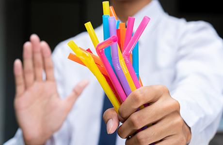 Person holding straws in one hand and refusing them with the other