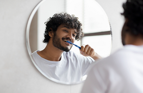 Young man brushing his teeth at home