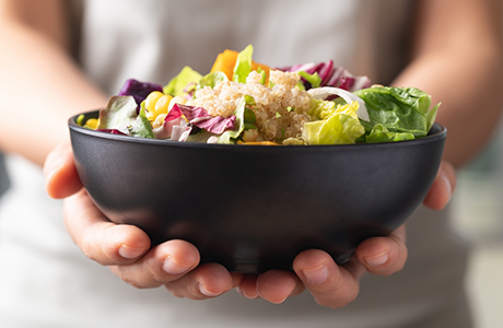 Person holding a bowl of salad