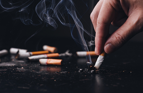 Person putting out a cigarette on a black tabletop
