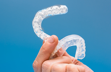 Hand holding two white mouthguard trays