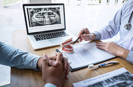Person sitting at a desk with their dentist during a consultation