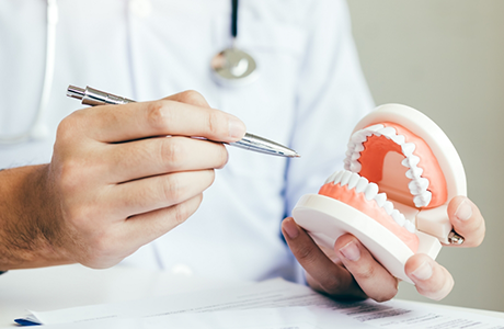Dentist holding a pen and pointing to a set of dentures