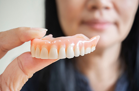 Woman holding a full upper denture