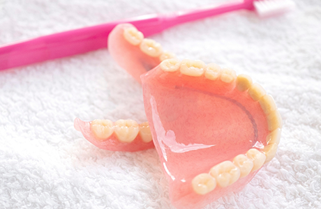 Dentures resting on a towel next to a toothbrush