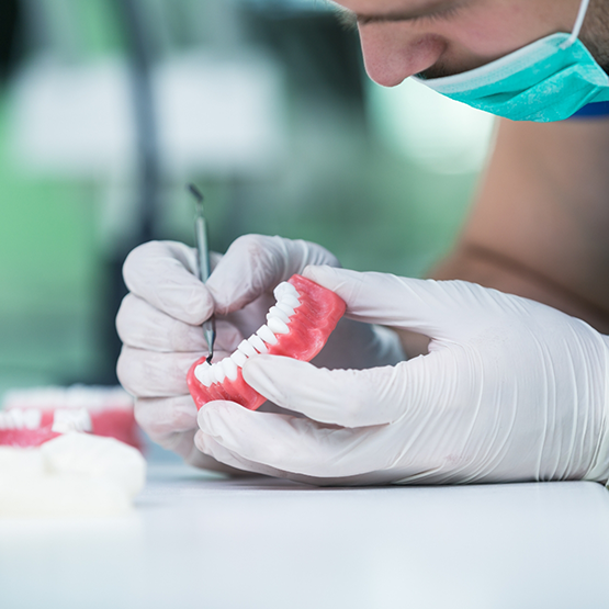 Dental lab worker closely adjusting a denture