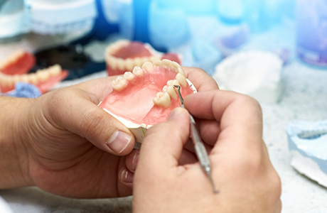 Dental professional using a small tool on a denture