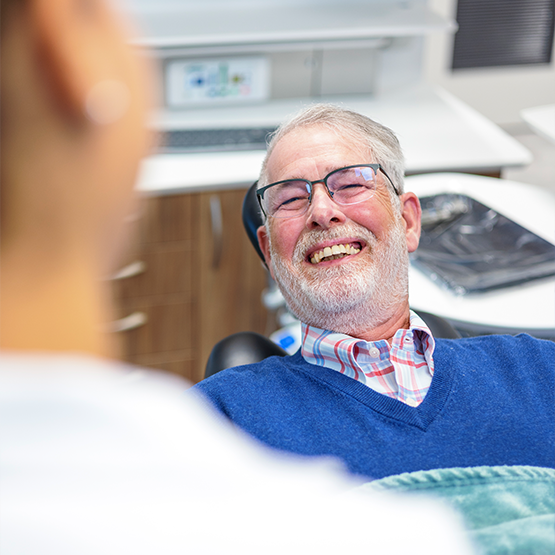 Senior dental patient smiling at his dentist