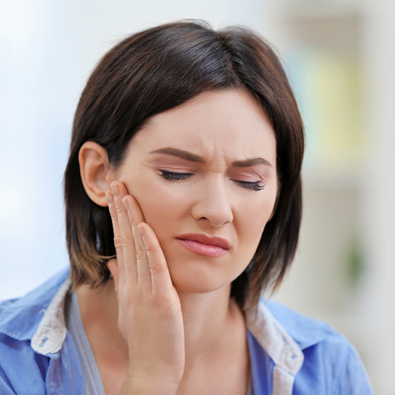 Woman holding her cheek and wincing in pain