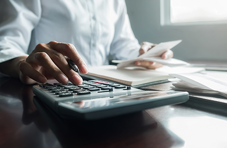 Person at a desk typing on a calculator