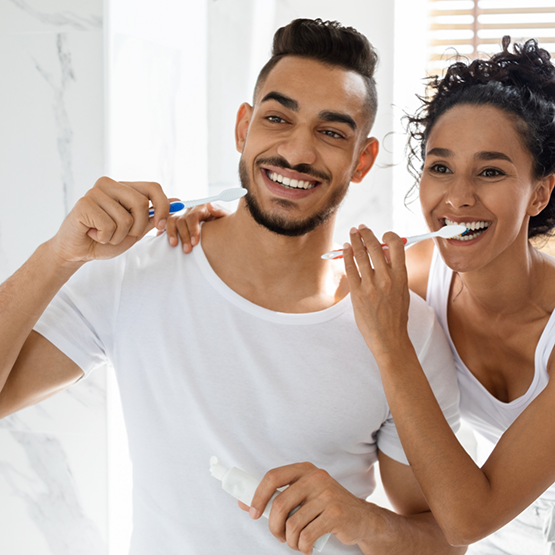 Man and woman brushing their teeth together at home