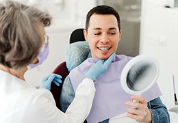 Man smiling at reflection in mirror with dentist