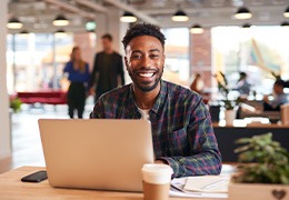 Man smiling while working on laptop at home