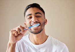 Man smiling while brushing his teeth