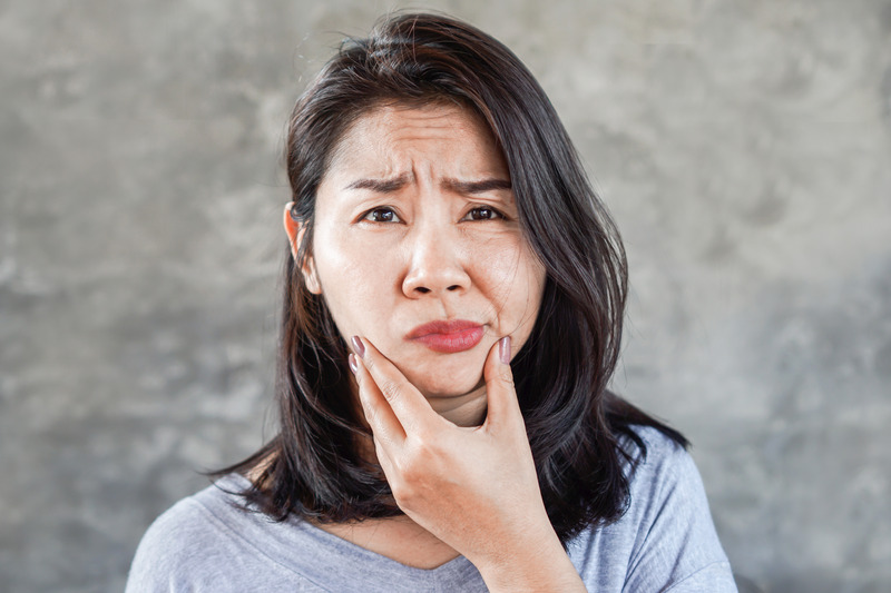 Patient holding their cheek due to tooth pain