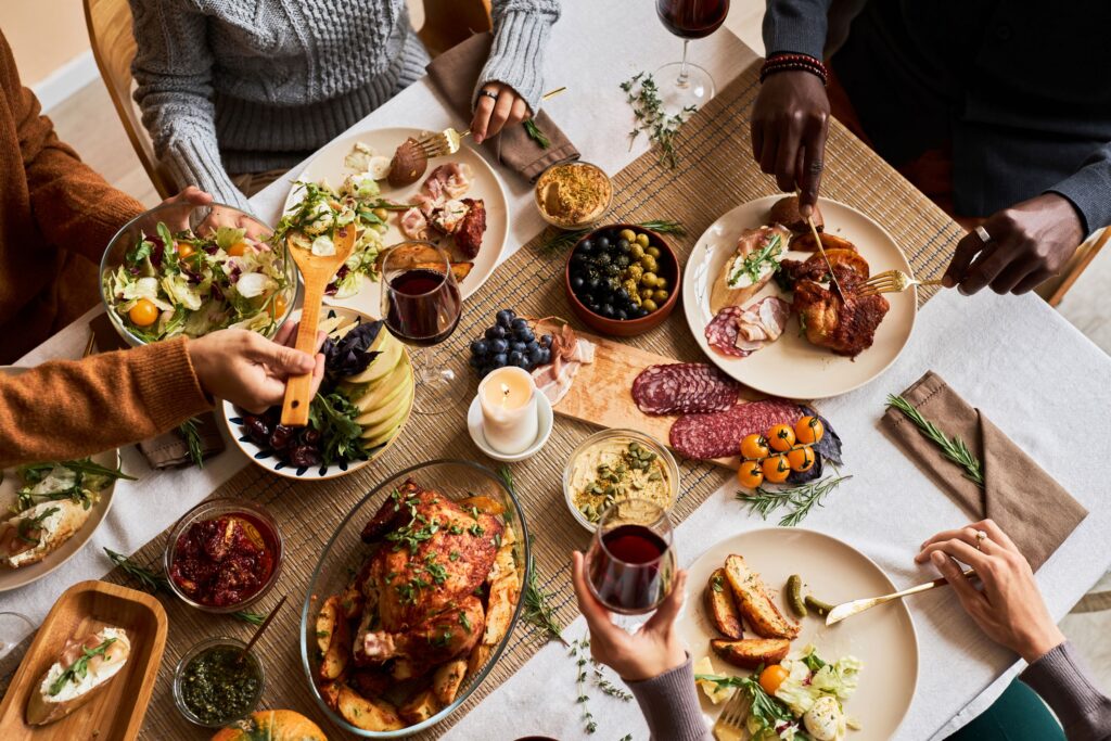 Bird's eye view of people sitting around Thanksgiving table serving food